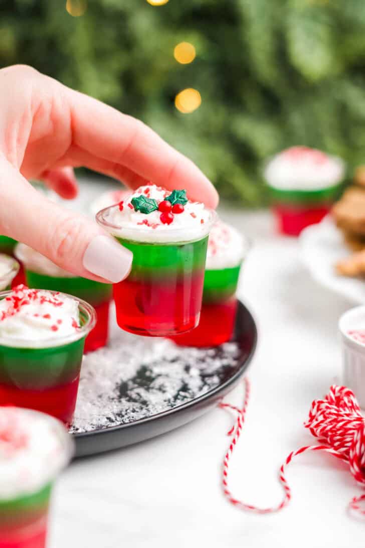 A hand holding a Christmas jello shot.