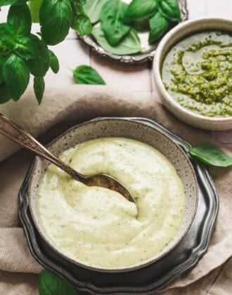 A bowl of pesto ranch with a spoon in it.