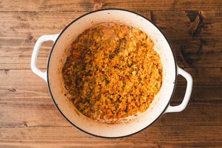 A Dutch oven filled with cooked, finely chopped vegetables.