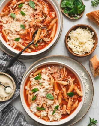 Two bowls of chicken parmesan soup on a light background.