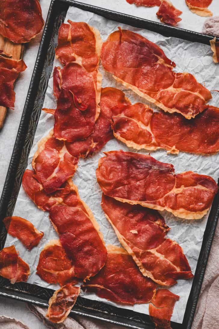 A baking pan covered in crispy prosciutto slices.