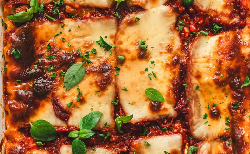 Baked cottage cheese lasagna in a white baking dish garnished with fresh basil.