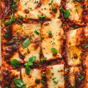 Baked cottage cheese lasagna in a white baking dish garnished with fresh basil.