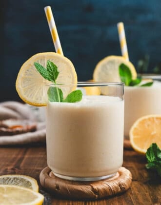 A lemon smoothie garnished with a fresh lemon wheel, mint, and a yellow straw.