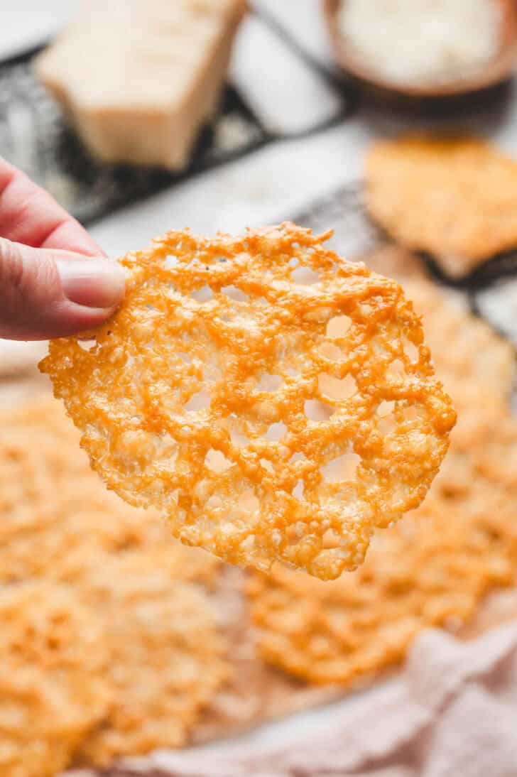 A hand holding up a Parmesan crisps recipe.