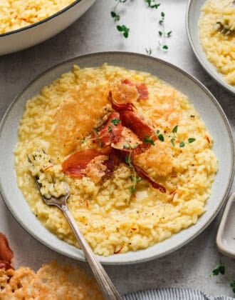 A bowl of risotto Milanese topped with crispy prosciutto and Parmesan crisps.
