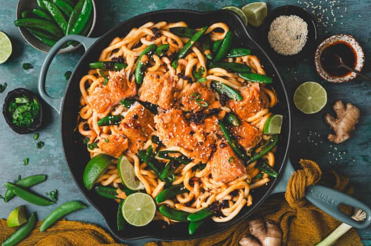 Coconut curry salmon over udon noodles in a skillet.