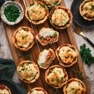 A cutting board filled with mini shepherd's pies.
