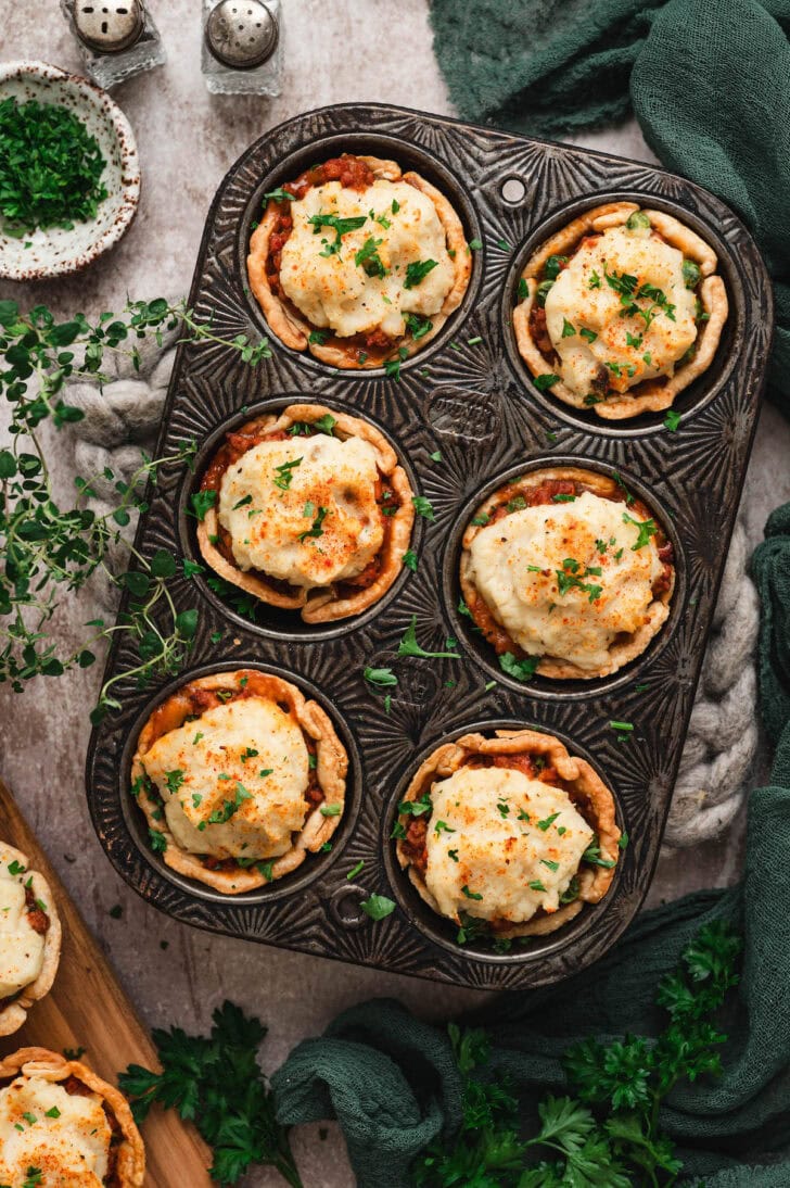 A textured muffin pan with six portions of mini shepherd's pie.