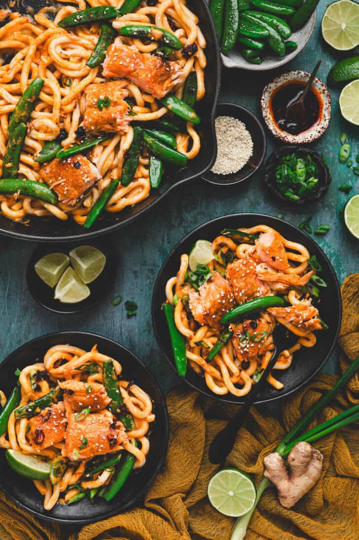 Two bowls filled with a coconut curry salmon recipe over udon noodles.