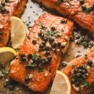 Several pieces of salmon piccata in a skillet.