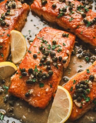 Several pieces of salmon piccata in a skillet.