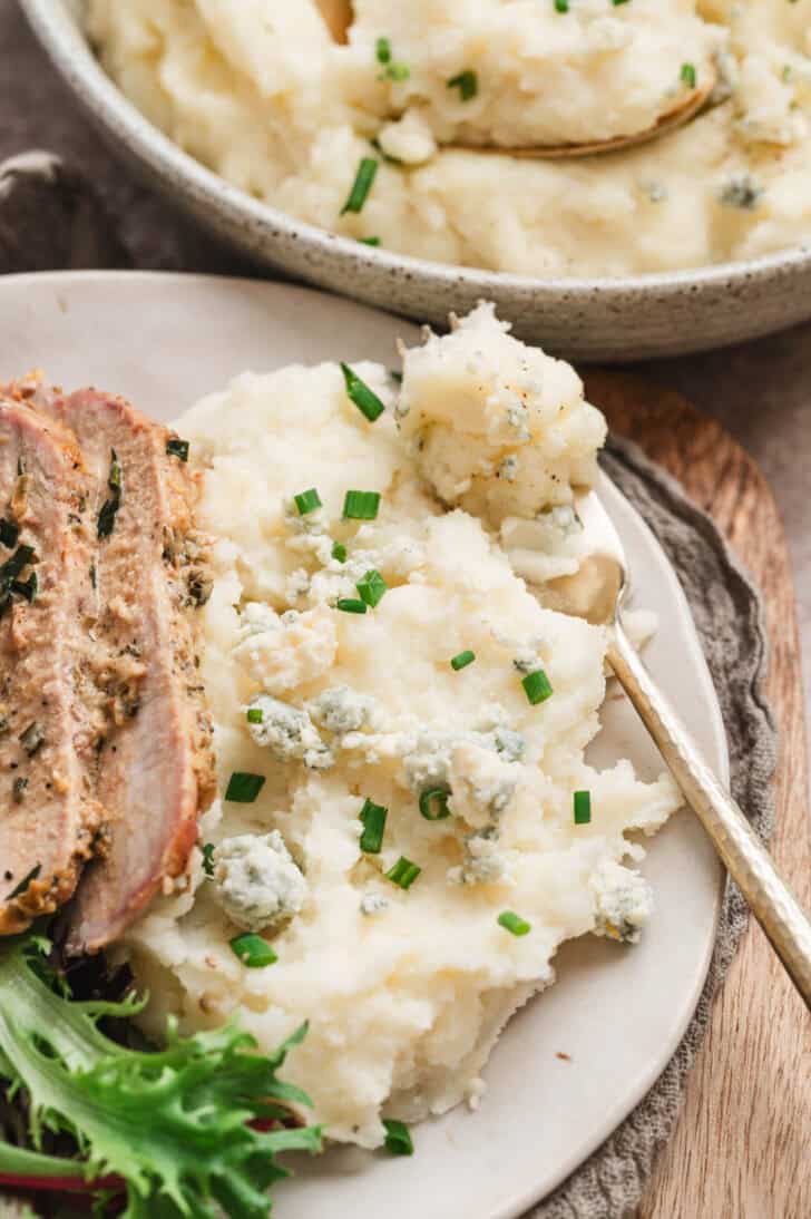 A plate filled with sliced pork loin and gorgonzola mashed potatoes.