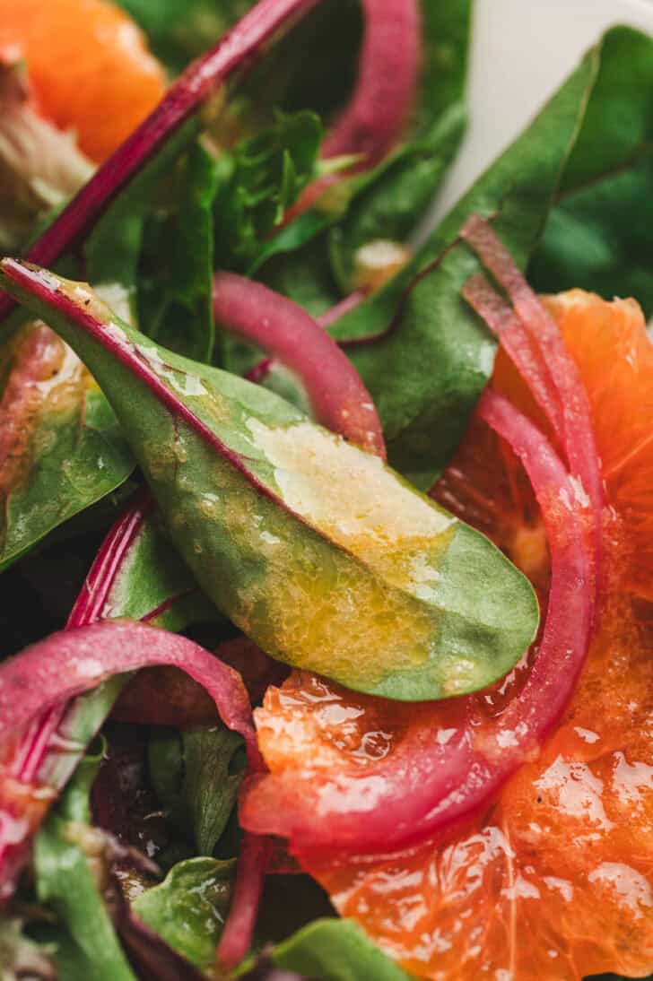 Closeup photo of citrus vinaigrette dressing clinging to a salad leaf.