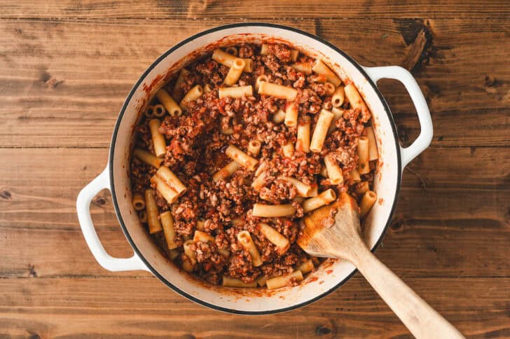 A pot of cooked ziti pasta tossed with meaty tomato sauce.