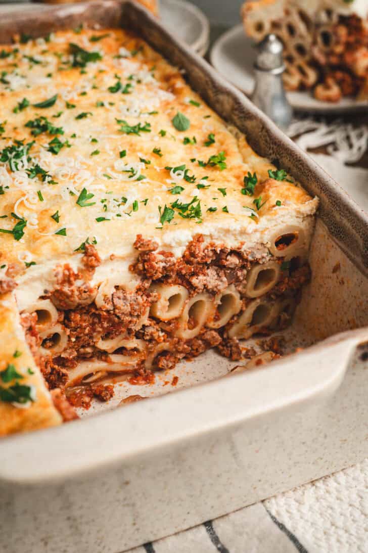 A baking dish with a cross section of a Greek pastitsio recipe cut out.