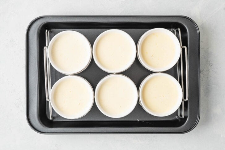 Lemon brulee custard in ramekins in a water bath in a baking dish.