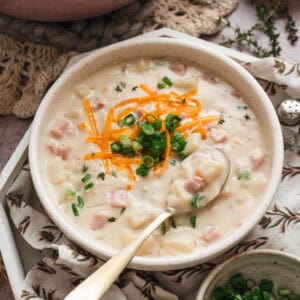 A bowl of potato ham soup with a spoon in it.