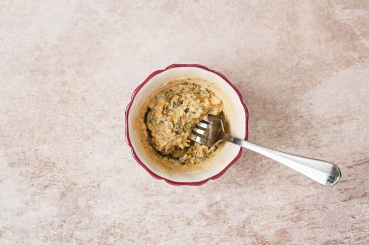 A small bowl filled with a mustard and herb mixture with a fork in it.
