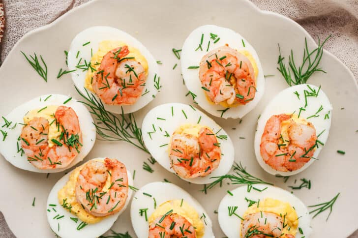 Deviled eggs and shrimp on a light platter.