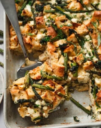 A server lifting a piece of strata recipe from a baking dish.