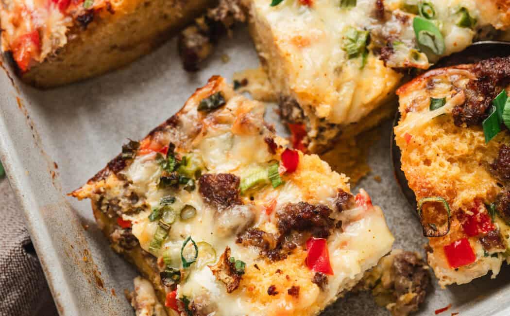 A baking pan filled with cornbread breakfast bake, cut into squares.