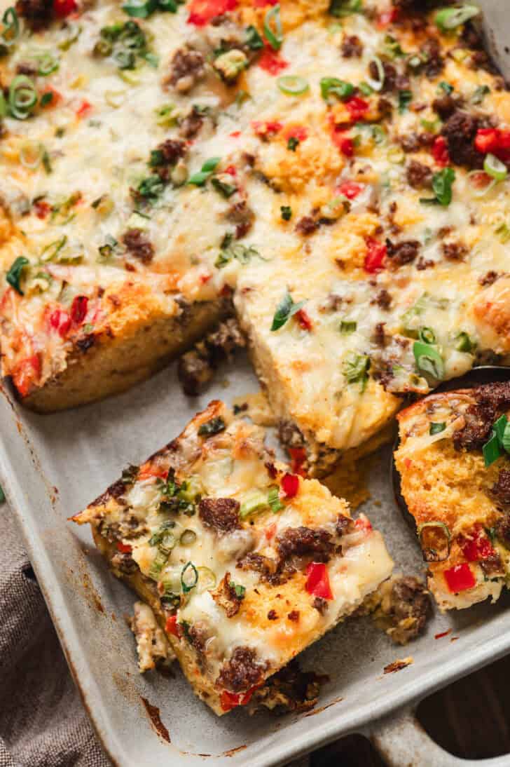 A baking pan filled with cornbread breakfast bake, cut into squares.