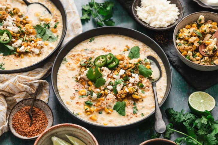 A bowl of a Mexican street corn soup recipe with a spoon in it.