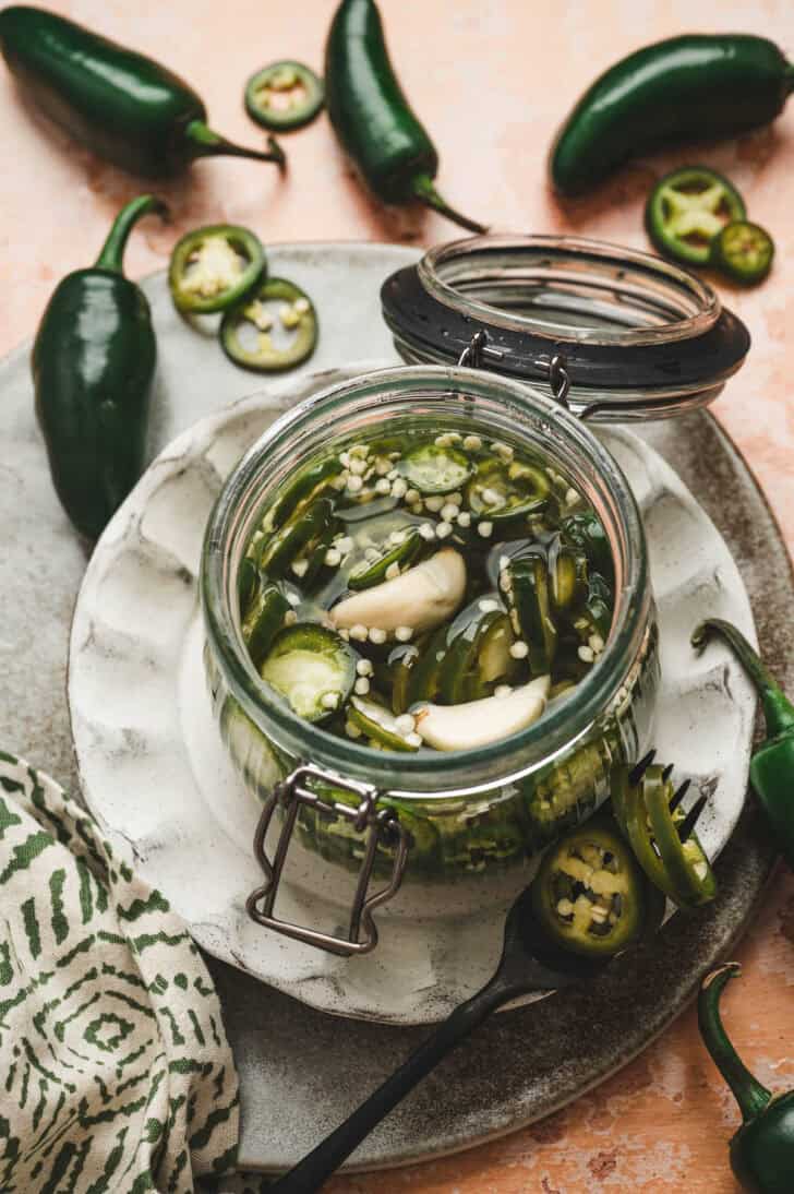 Pickled jalapeno peppers and garlic in a glass jar.