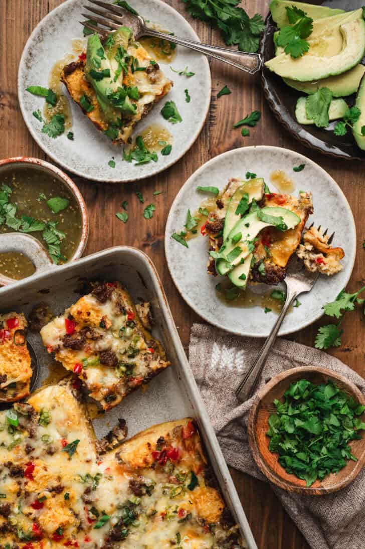 Two plates and a baking dish of cornbread breakfast bake.