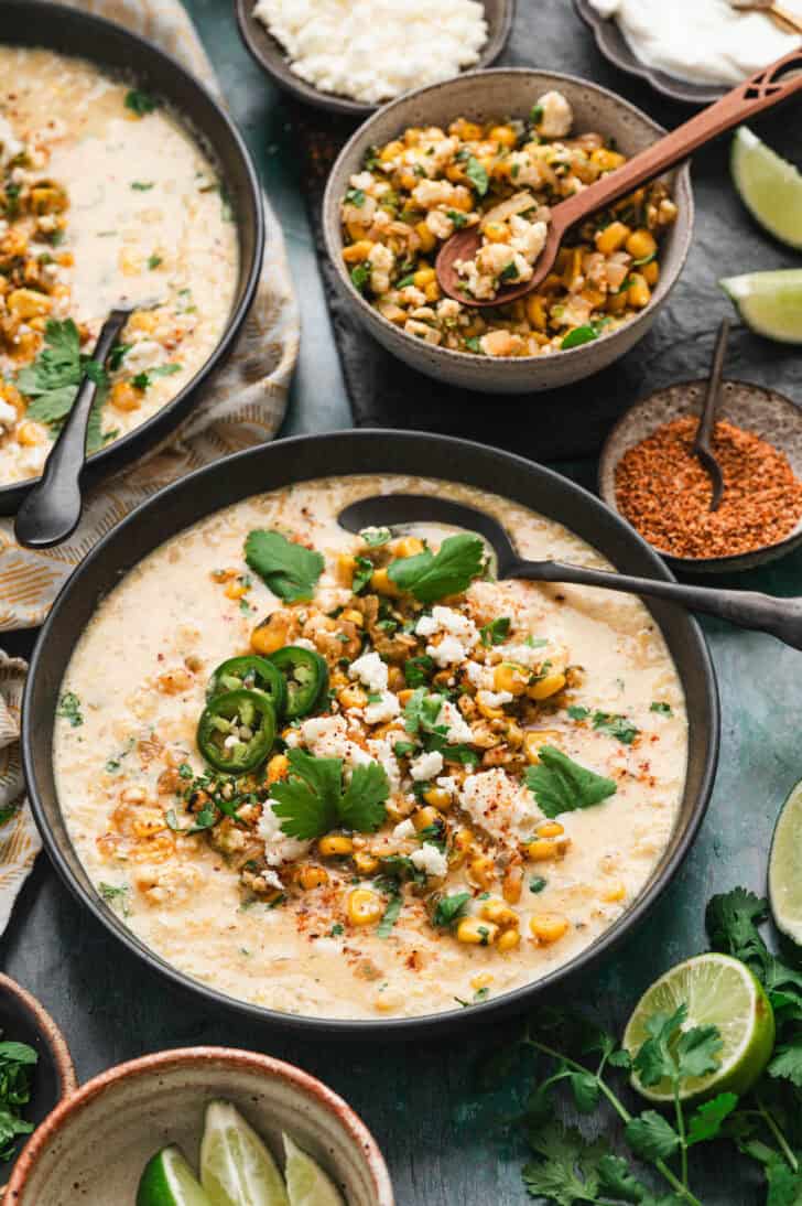 A bowl of Mexican street corn soup with a spoon in it.