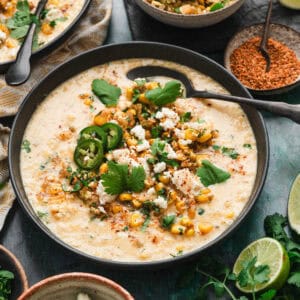 A bowl of Mexican street corn soup with a spoon in it.