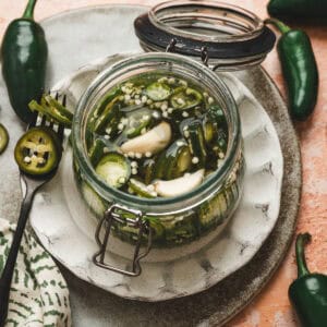 Pickled jalapeno peppers and garlic in a glass jar.
