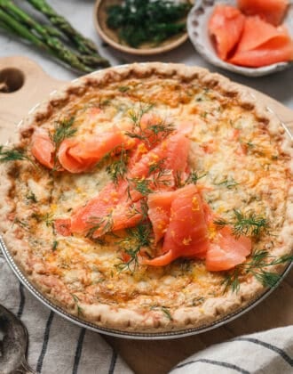 A salmon quiche on a wooden cutting board.