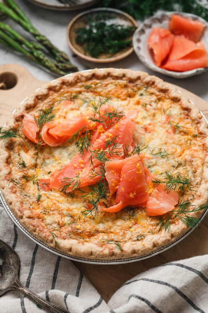 A salmon quiche on a wooden cutting board.
