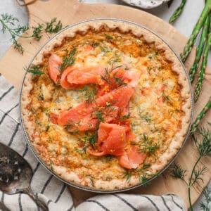 A salmon quiche on a wooden cutting board.