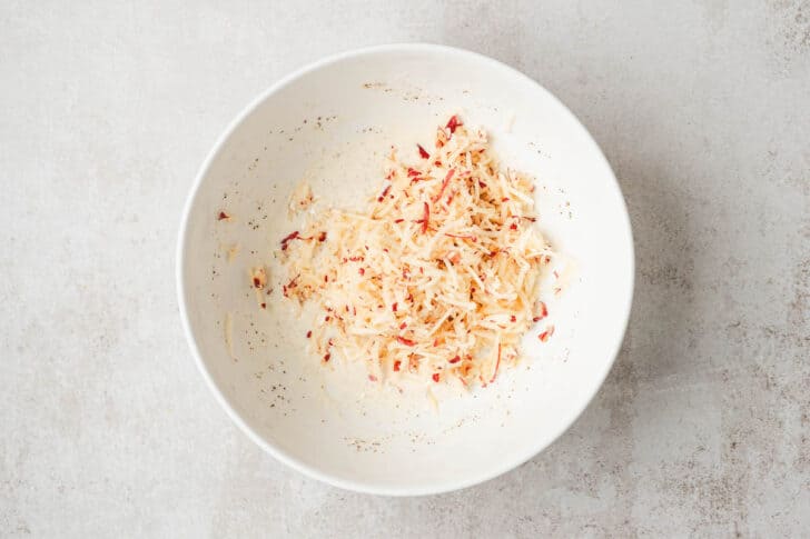 Shredded apple in a white bowl.