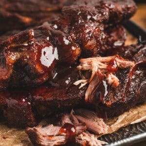 A pile of country style ribs in oven on a baking pan.