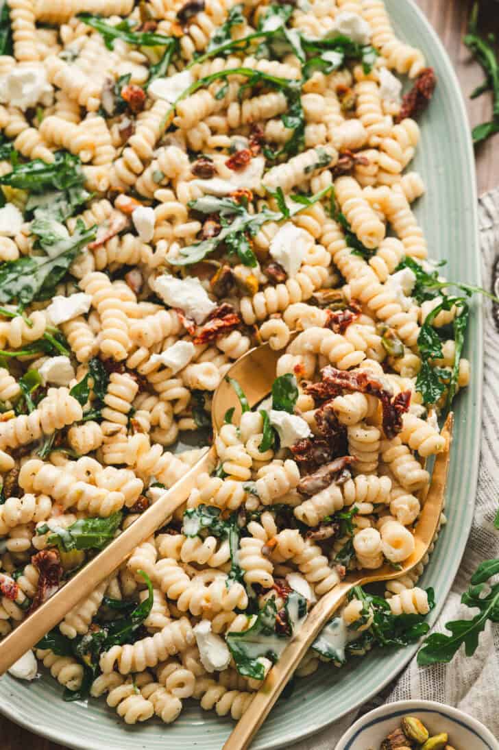 A light blue platter filled with goat cheese pasta salad.
