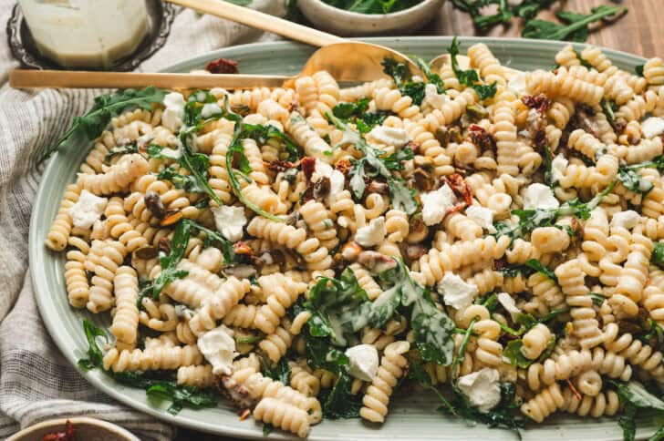 A light blue platter filled with lemon arugula pasta salad.