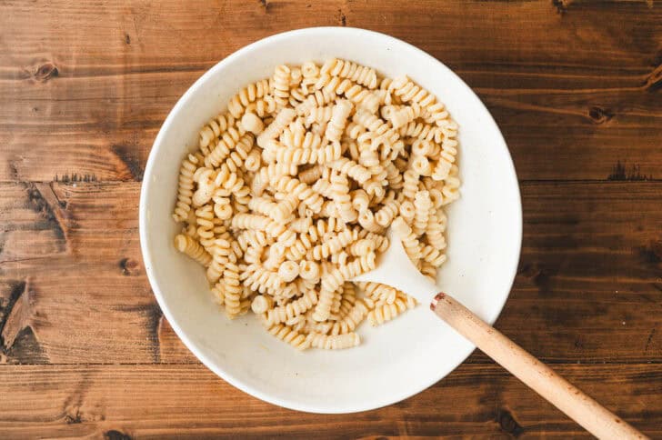 Pasta salad with goat cheese dressing in a white bowl.