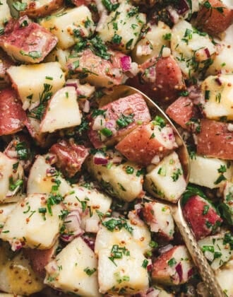 A no mayo potato salad recipe with a spoon in it.