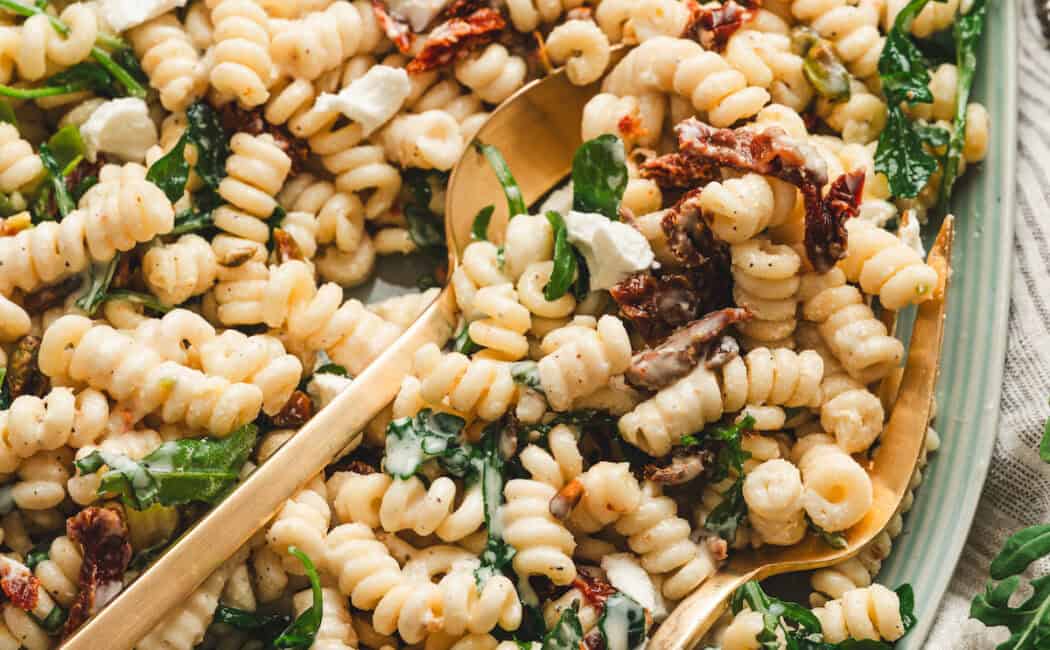 A light blue platter filled with goat cheese pasta salad.