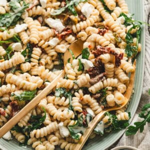 A light blue platter filled with goat cheese pasta salad.