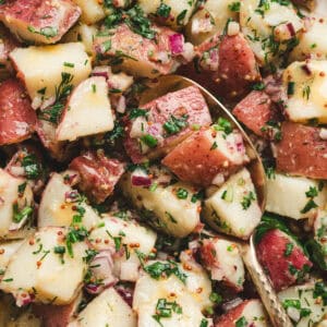 A no mayo potato salad recipe with a spoon in it.