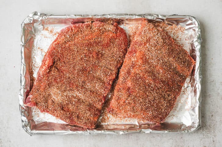 Spare ribs rubbed with spices on a baking pan.