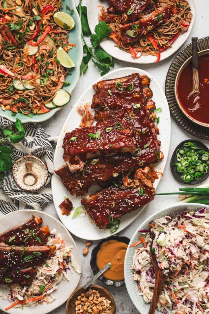 A platter of Asian BBQ ribs with side dishes all around it.
