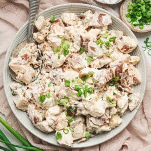 A white bowl filled with potato salad with bacon.