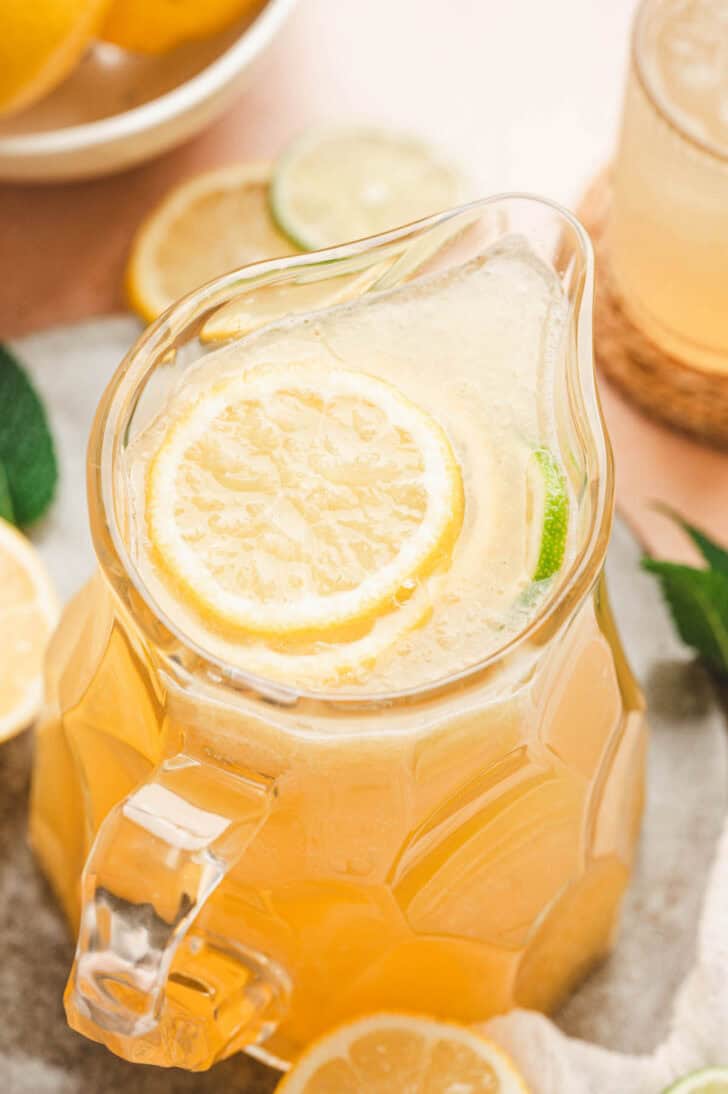 A glass pitcher filled with a yellow-hued beverage.