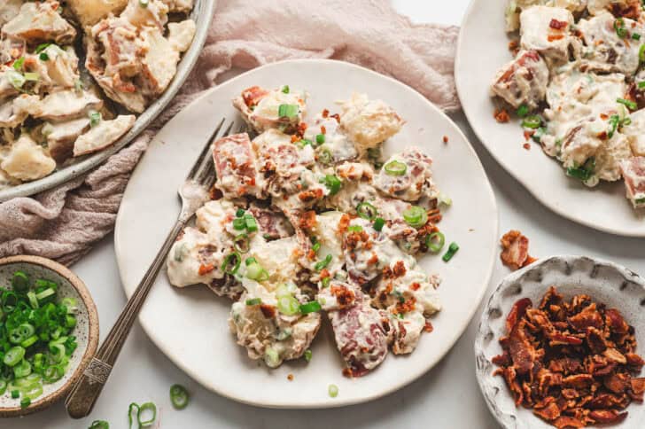 Red potato salad with bacon on a white plate.